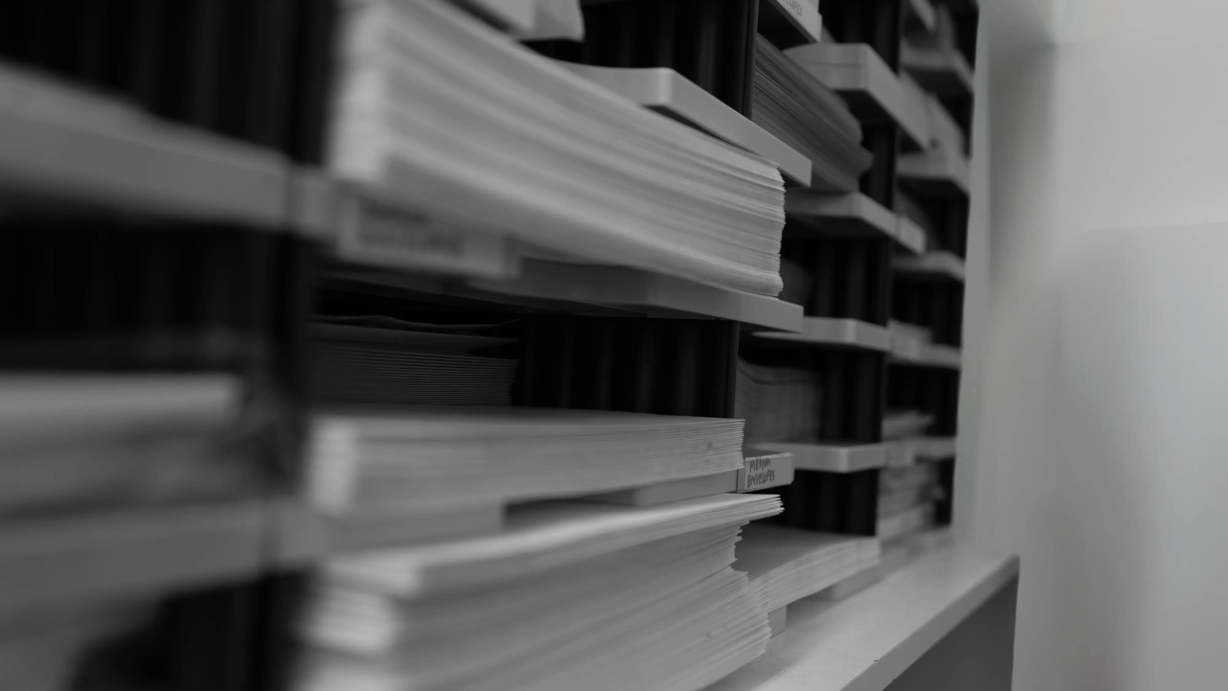 Reports and certificates for HIYOS GP Practice. Close-up view of a filing system with stacked papers in black and white.
